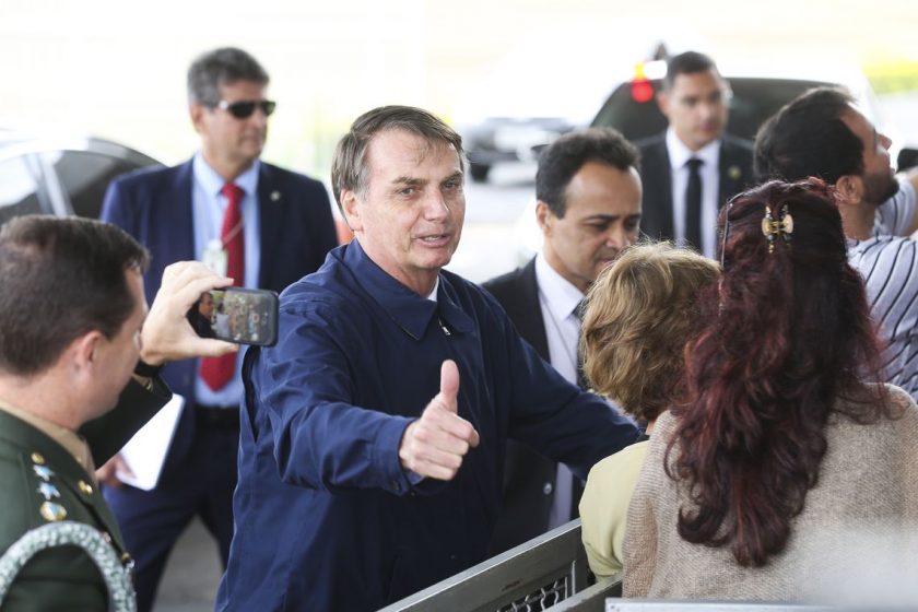 O presidente Jair Bolsonaro recebe cumprimento de turistas na entrada do Palácio da Alvorada.